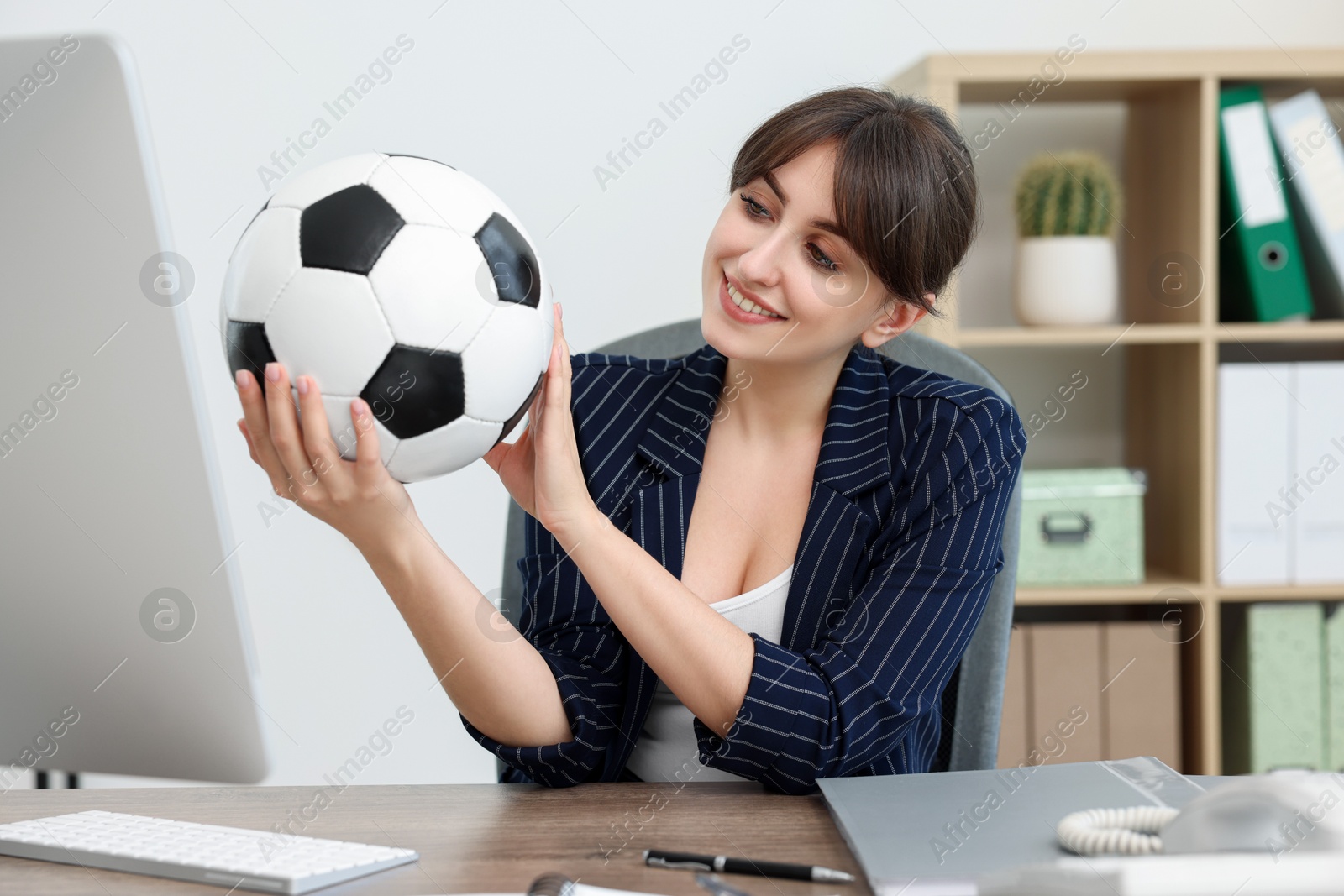 Photo of Smiling employee with soccer ball at table in office