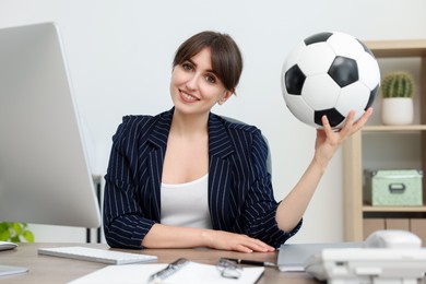 Photo of Smiling employee with soccer ball at table in office