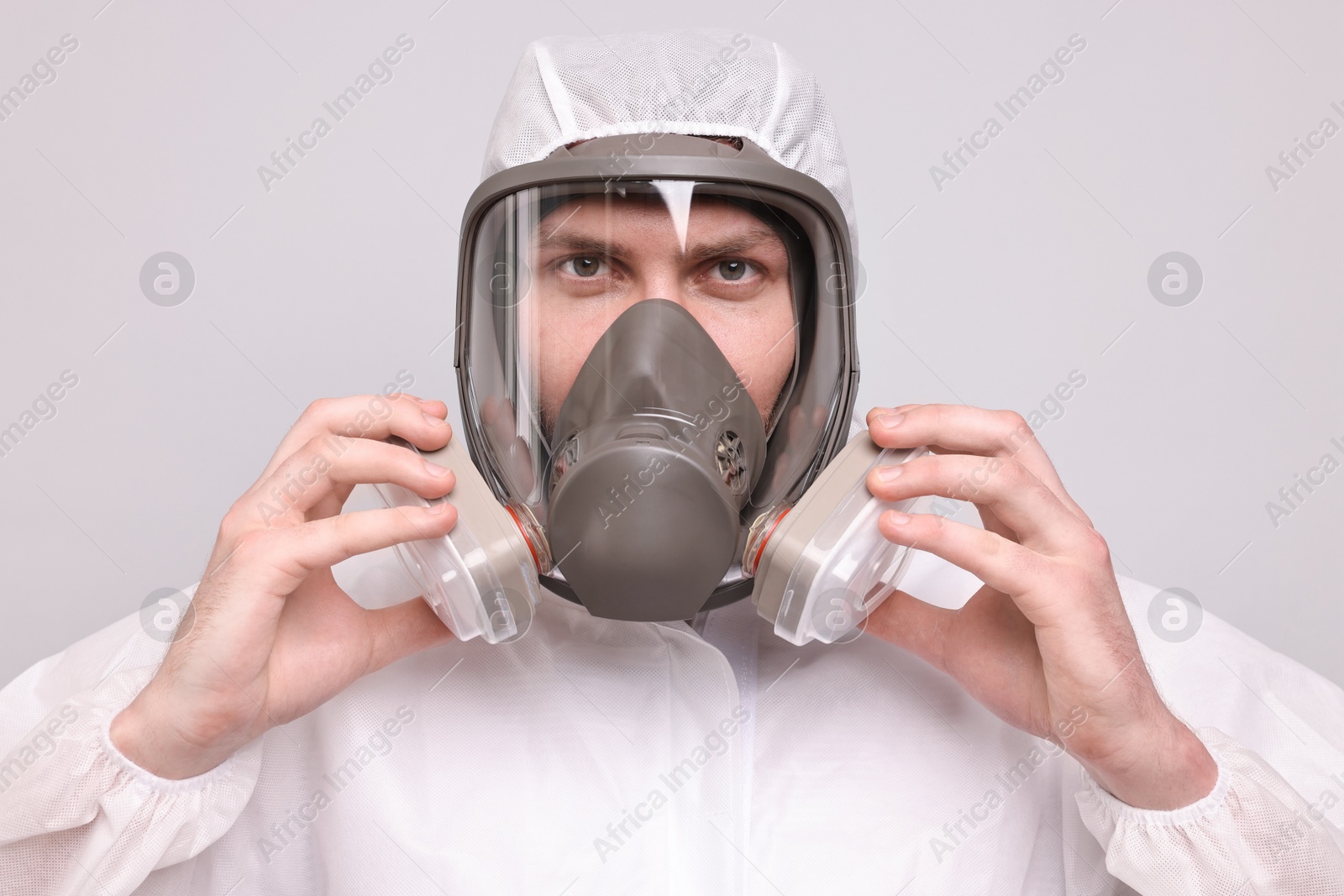 Photo of Man wearing protective suit with respirator mask on light background