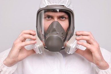 Photo of Man wearing protective suit with respirator mask on light background