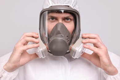 Man wearing protective suit with respirator mask on light background