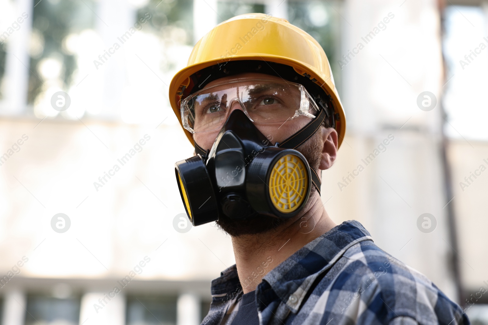 Photo of Man in respirator mask and hard hat outdoors. Safety equipment