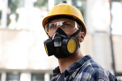 Photo of Man in respirator mask and hard hat outdoors. Safety equipment