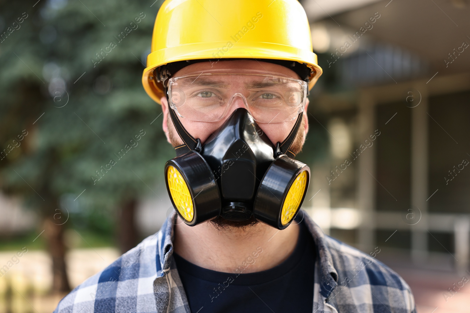 Photo of Man in respirator mask and hard hat outdoors. Safety equipment