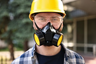 Photo of Man in respirator mask and hard hat outdoors. Safety equipment