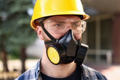 Photo of Man in respirator mask and hard hat outdoors. Safety equipment