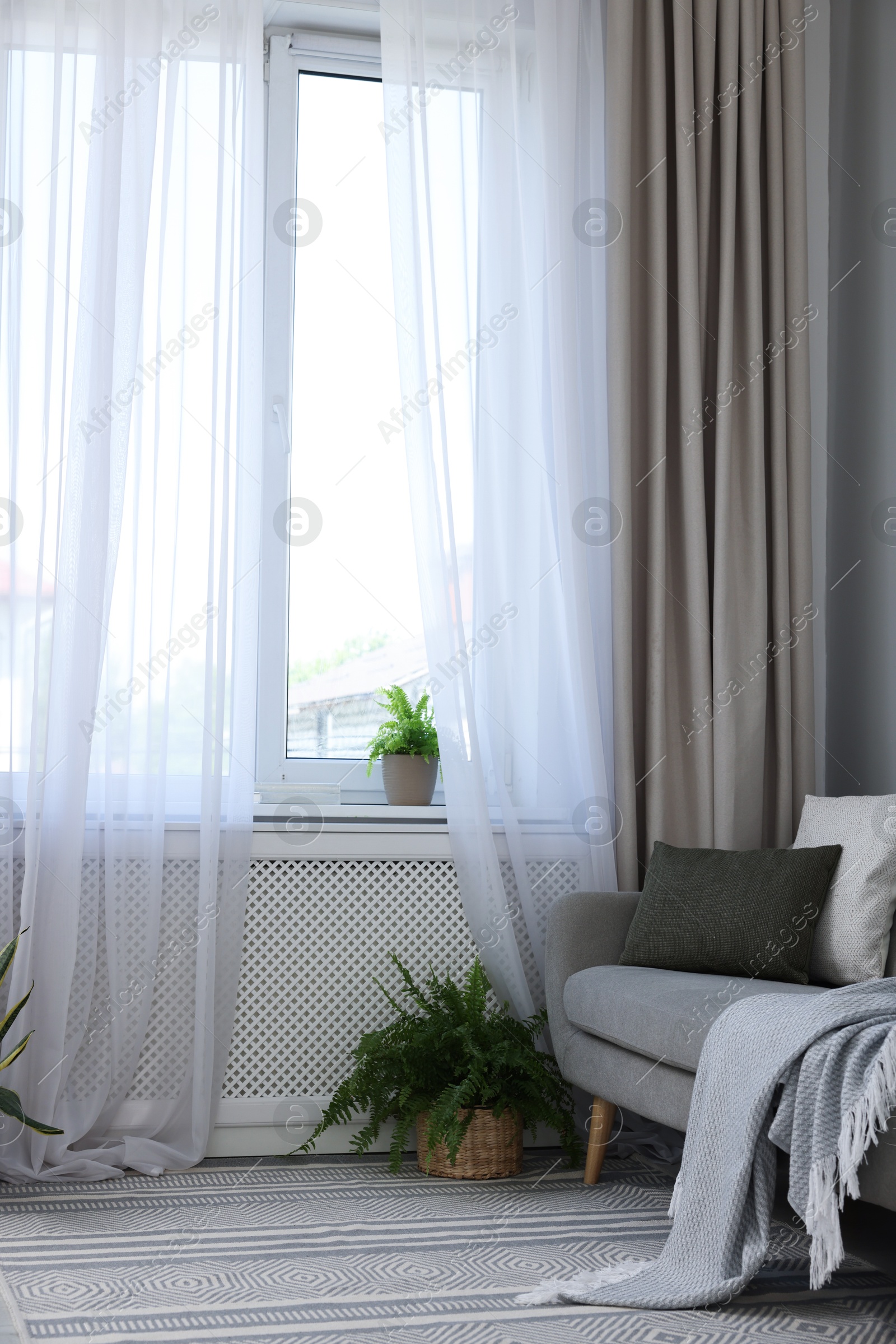 Photo of Comfortable sofa and elegant curtains in living room. Interior design