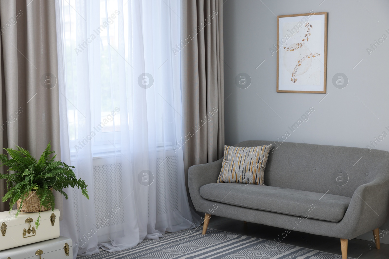 Photo of Comfortable sofa and elegant curtains in living room. Interior design