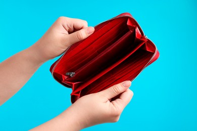 Photo of Woman with empty wallet on light blue background, closeup