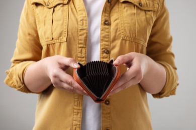 Photo of Woman with empty wallet on grey background, closeup