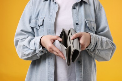 Photo of Woman with empty wallet on orange background, closeup