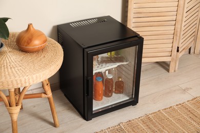 Photo of Mini refrigerator with drinks and snacks indoors