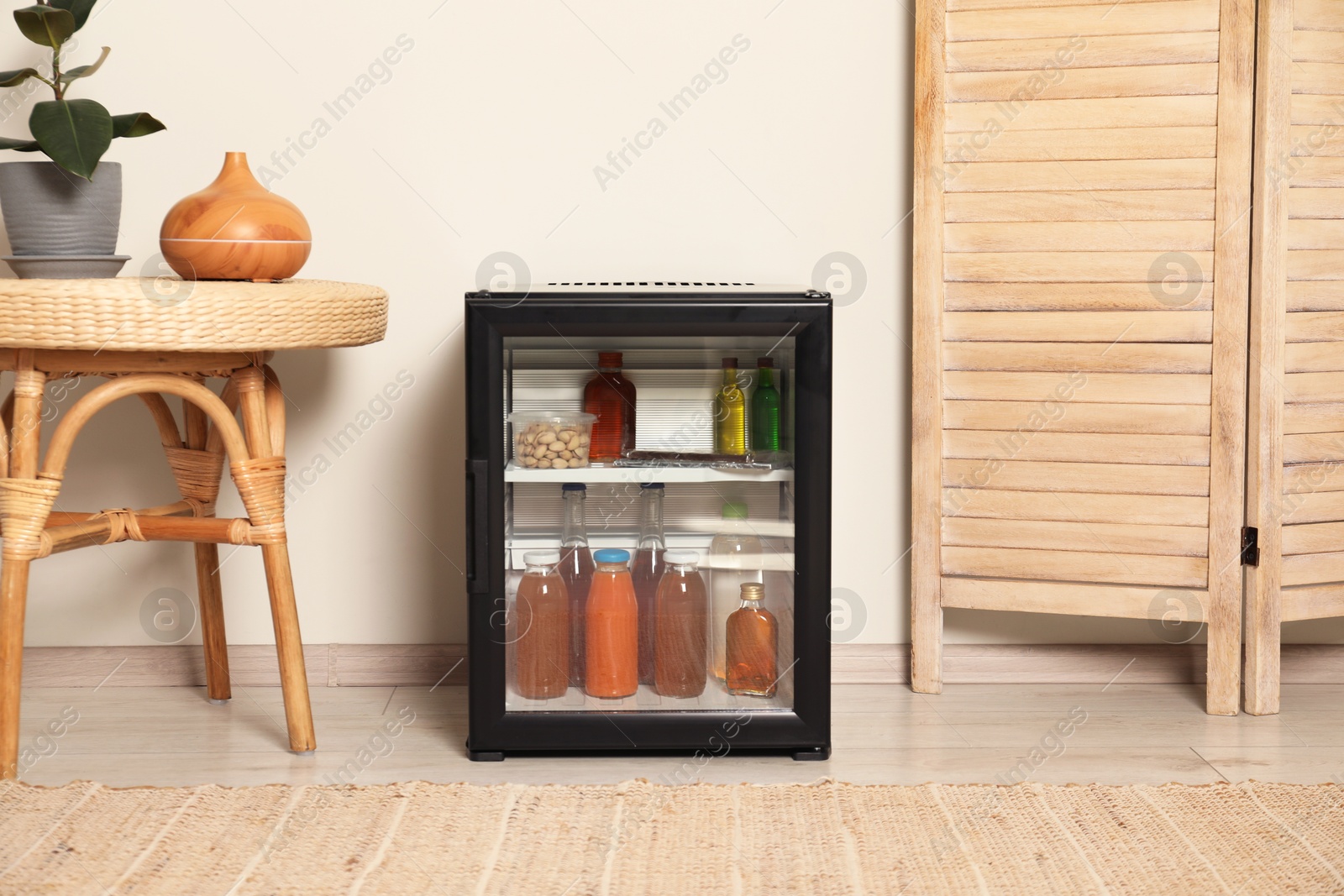 Photo of Mini refrigerator with drinks and snacks indoors