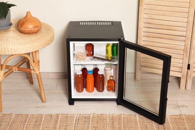 Photo of Mini refrigerator with drinks and snacks indoors