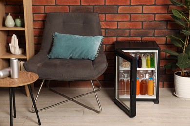 Photo of Mini refrigerator with drinks and snacks indoors