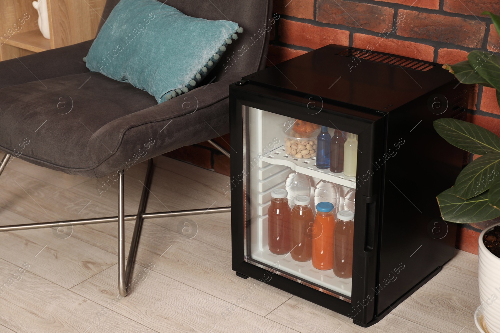 Photo of Mini refrigerator with drinks and snacks indoors