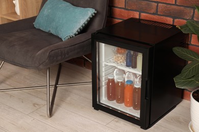 Photo of Mini refrigerator with drinks and snacks indoors