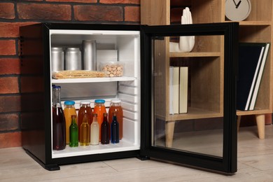 Photo of Mini refrigerator with drinks and snacks indoors