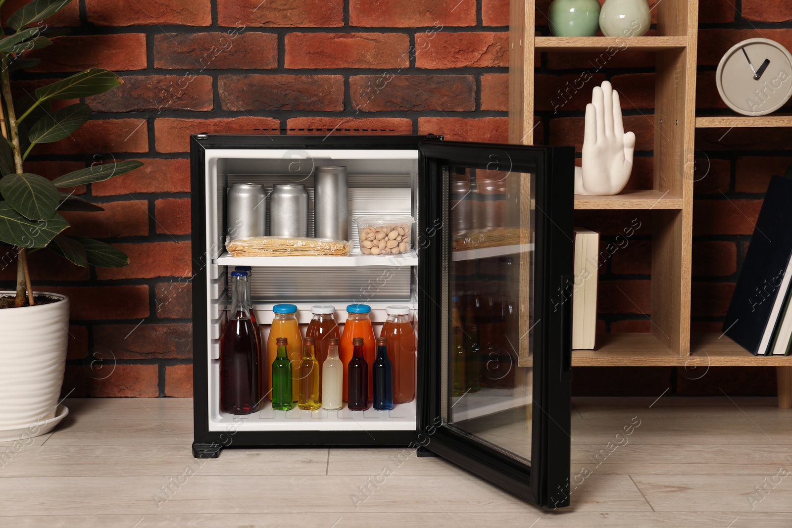 Photo of Mini refrigerator with drinks and snacks indoors