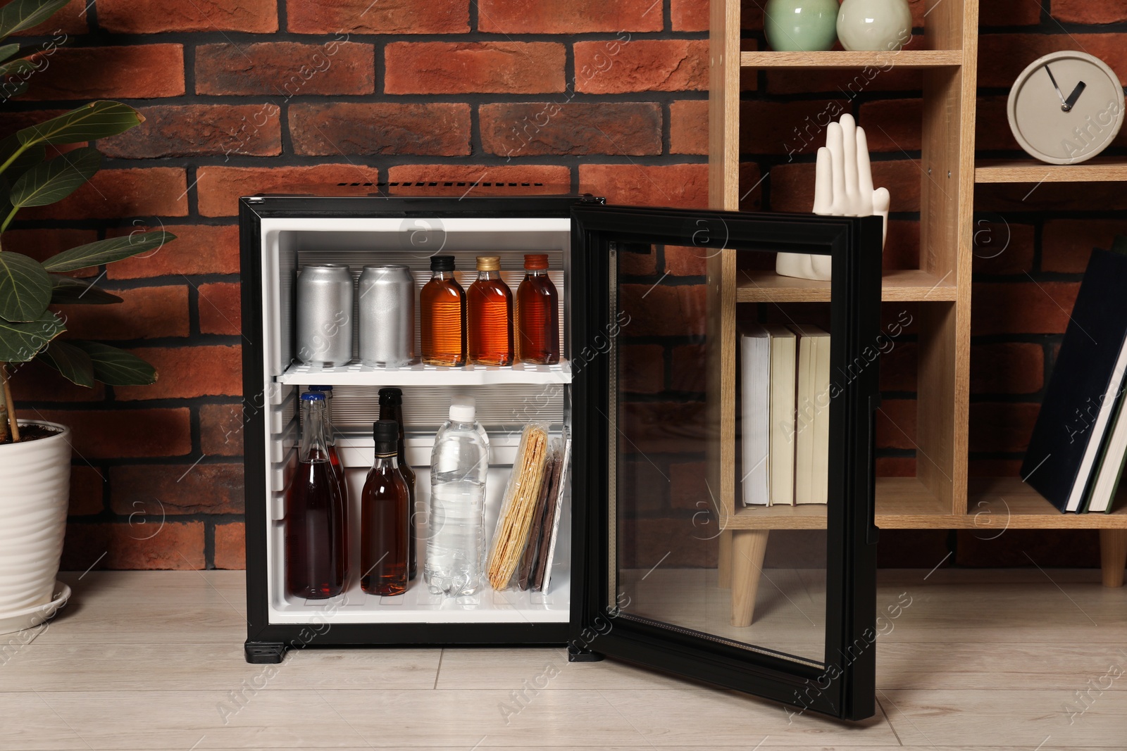 Photo of Mini refrigerator with drinks and snacks indoors