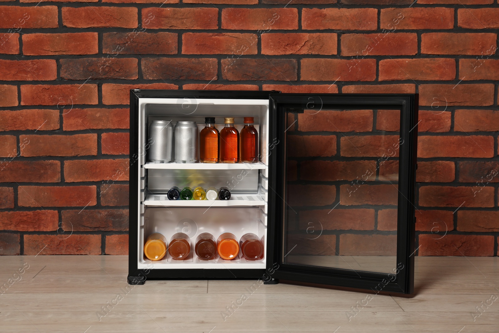 Photo of Mini refrigerator with drinks near brick wall