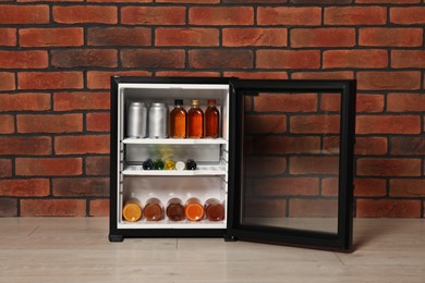 Mini refrigerator with drinks near brick wall