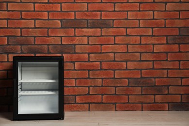 Photo of Empty mini refrigerator near brick wall. Space for text