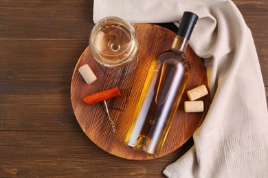 Photo of Corkscrew, glass of wine, bottle and corks on wooden table, top view