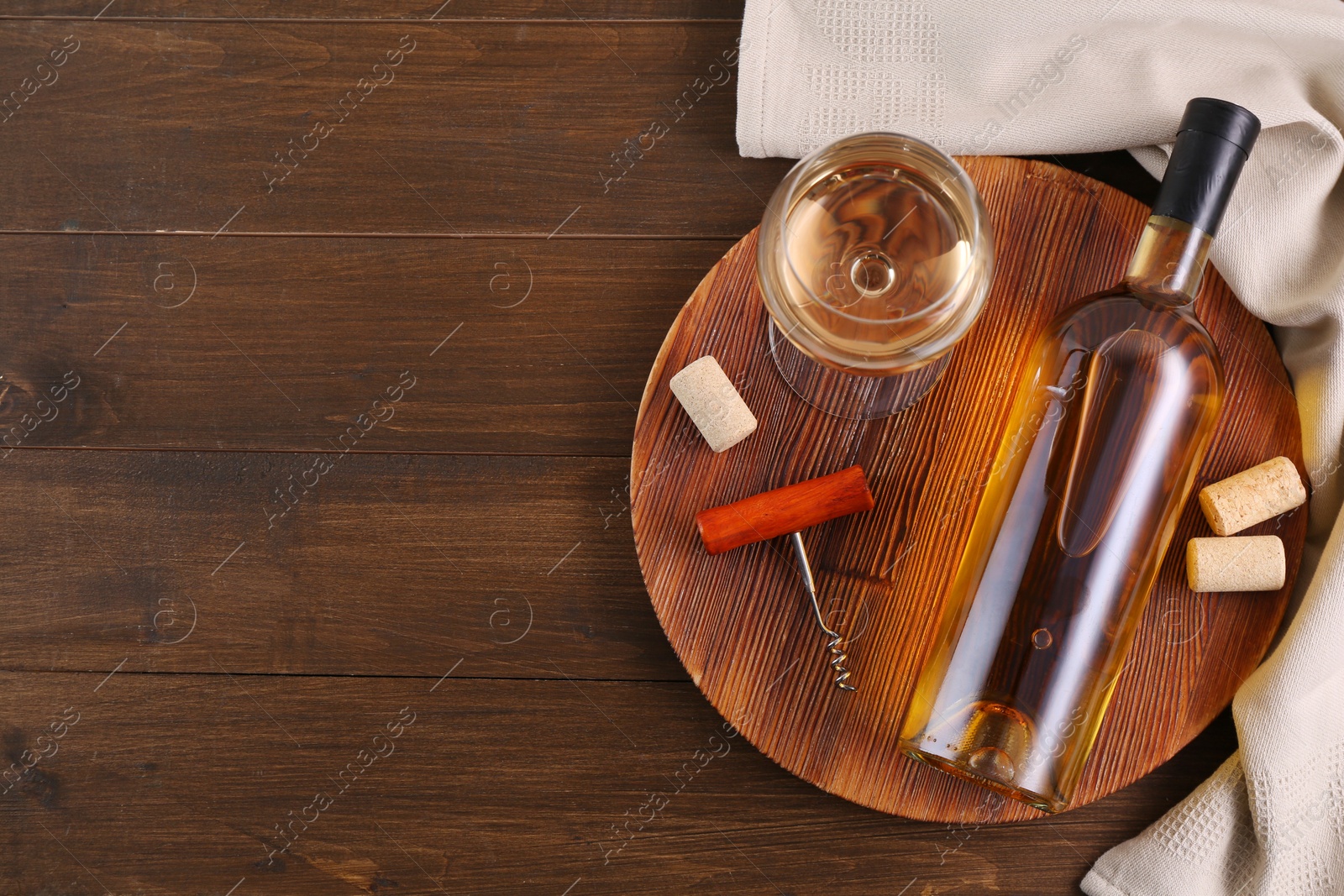 Photo of Corkscrew, glass of wine, bottle and corks on wooden table, top view. Space for text