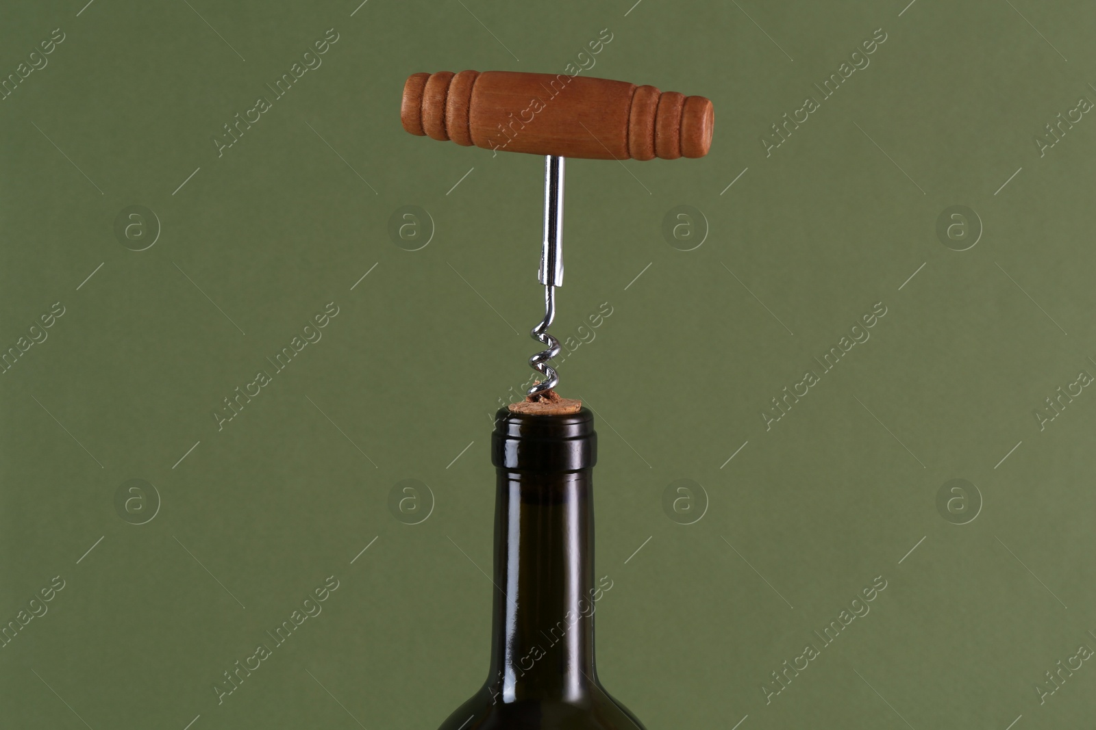 Photo of Wine bottle with corkscrew on olive background, closeup