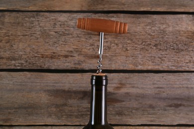 Photo of Wine bottle with corkscrew on wooden background