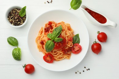 Photo of Delicious pasta with tomato sauce, peppercorns, vegetables and basil on white wooden table, flat lay