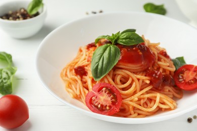 Photo of Delicious pasta with tomato sauce, peppercorns, vegetables and basil on white wooden table, closeup