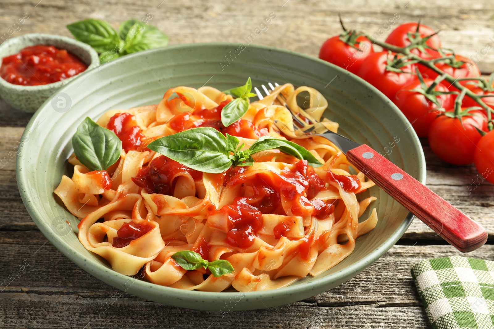 Photo of Delicious pasta with tomato sauce and basil in bowl on wooden table, closeup