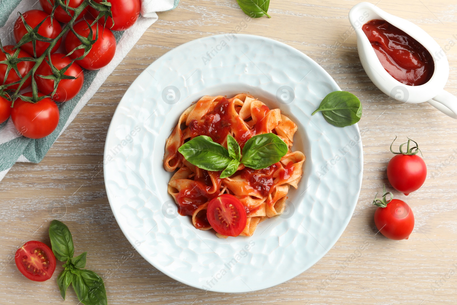 Photo of Delicious pasta with sauce, tomato and basil on wooden table, flat lay