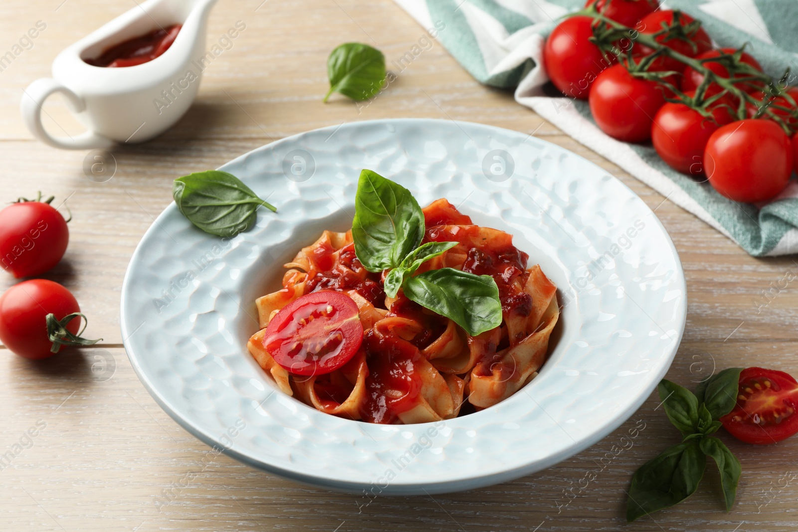 Photo of Delicious pasta with sauce, tomato and basil on wooden table, closeup