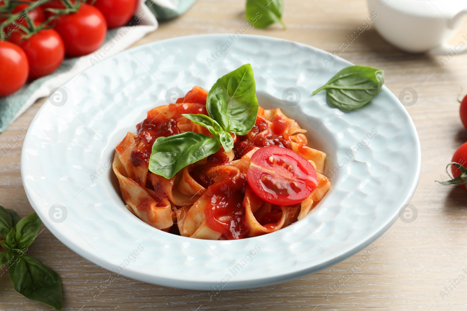 Photo of Delicious pasta with sauce, tomato and basil on wooden table, closeup