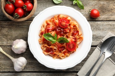 Photo of Delicious pasta with tomato sauce served on wooden table, flat lay