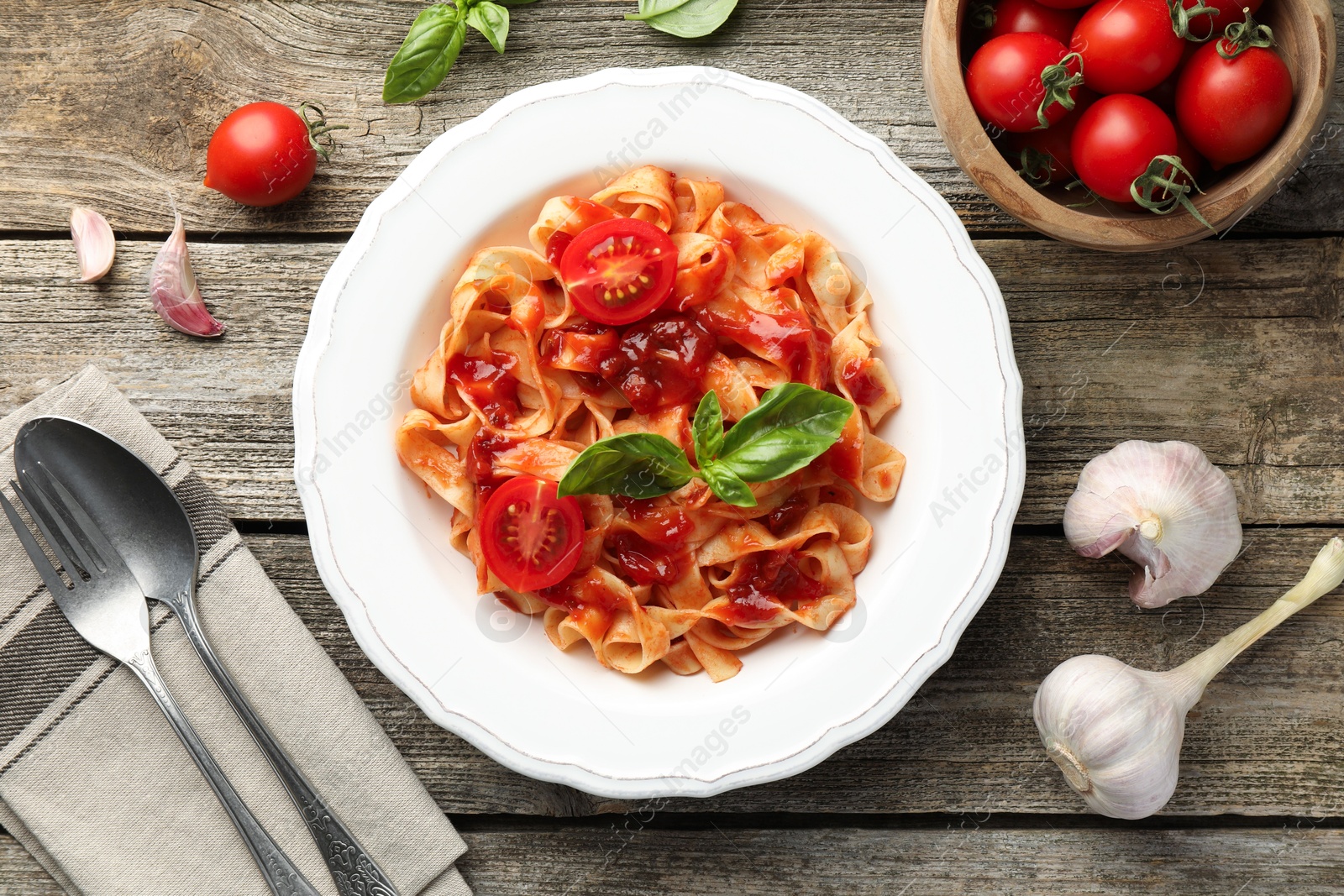 Photo of Delicious pasta with tomato sauce served on wooden table, flat lay