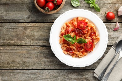 Delicious pasta with tomato sauce served on wooden table, flat lay. Space for text