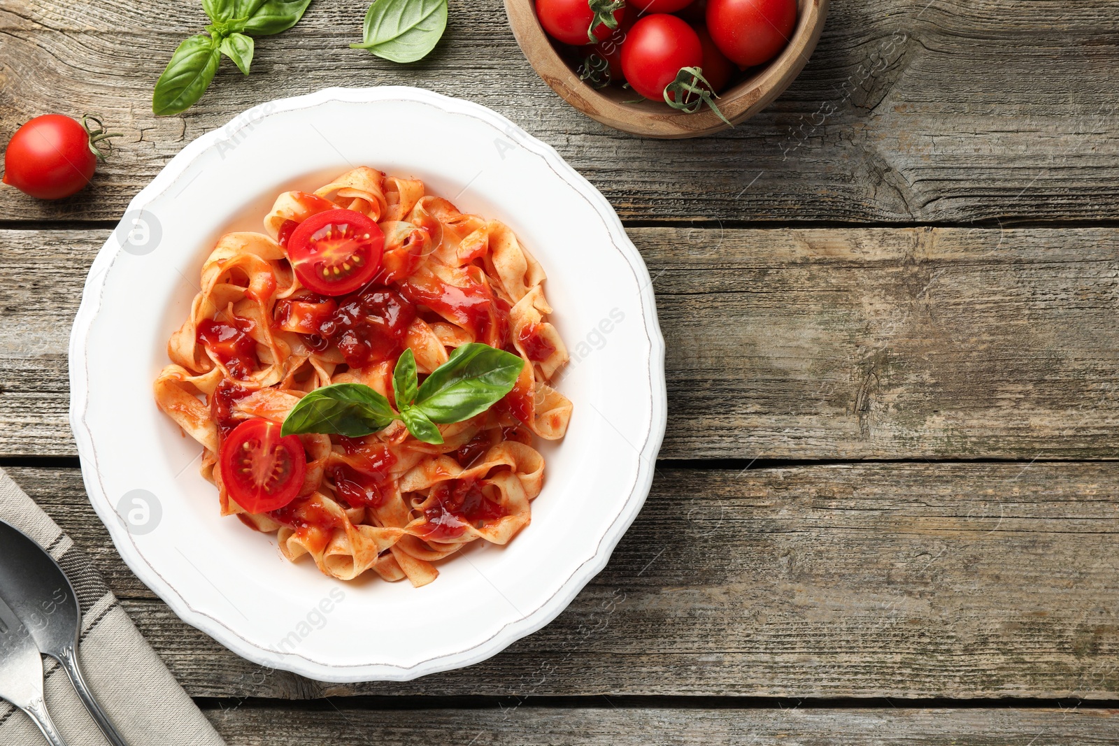 Photo of Delicious pasta with tomato sauce served on wooden table, flat lay. Space for text