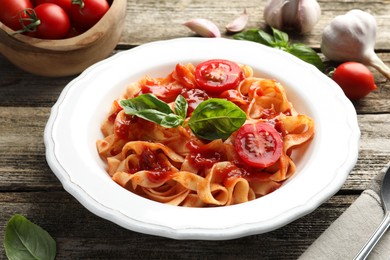 Photo of Delicious pasta with tomato sauce and basil on wooden table, closeup