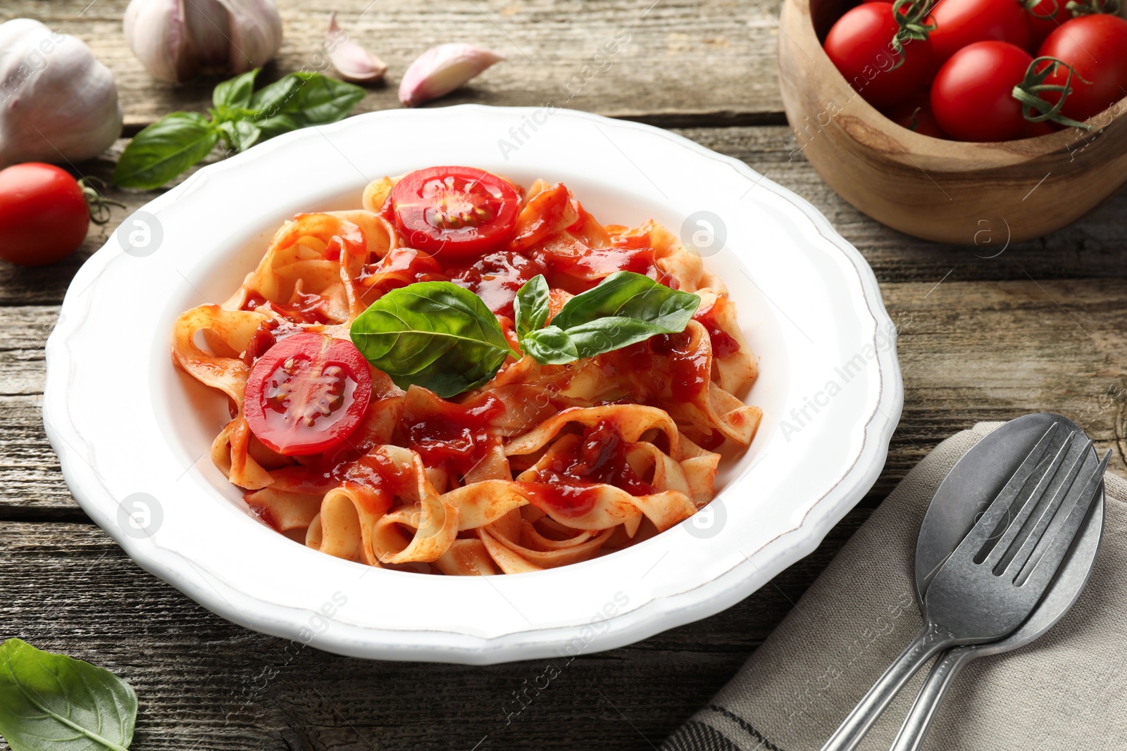 Photo of Delicious pasta with tomato sauce and basil on wooden table, closeup