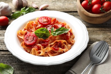 Photo of Delicious pasta with tomato sauce and basil on wooden table, closeup