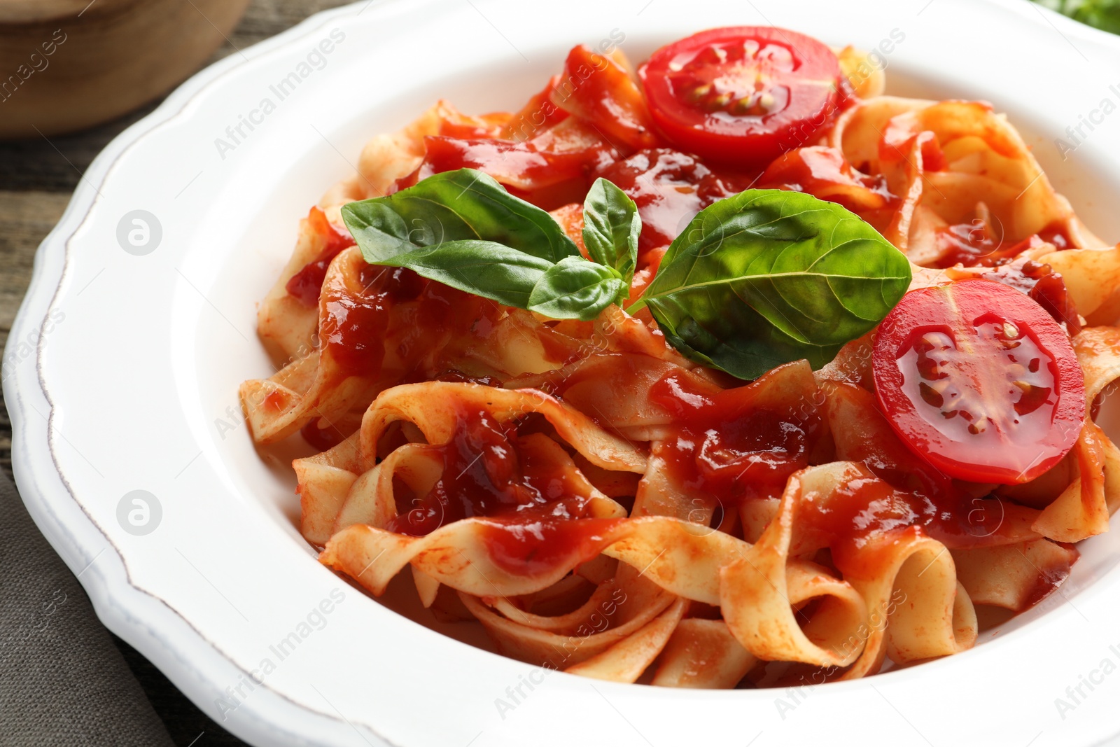 Photo of Delicious pasta with tomato sauce and basil on table, closeup