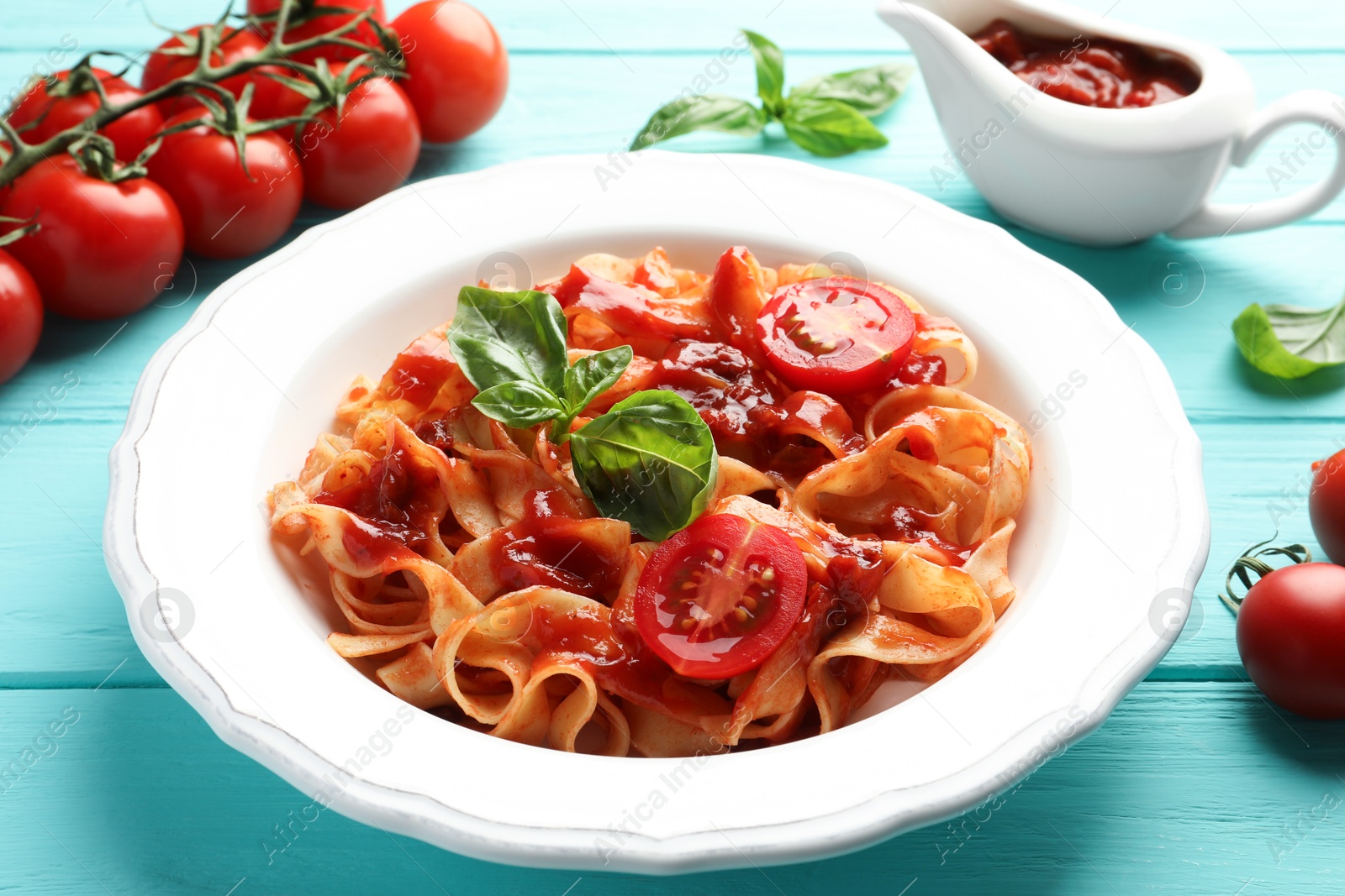 Photo of Delicious pasta with tomato sauce and basil on turquoise wooden table, closeup