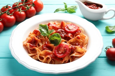 Photo of Delicious pasta with tomato sauce and basil on turquoise wooden table, closeup