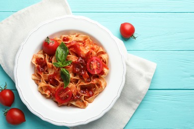 Photo of Delicious pasta with tomato sauce and basil on turquoise wooden table, flat lay. Space for text