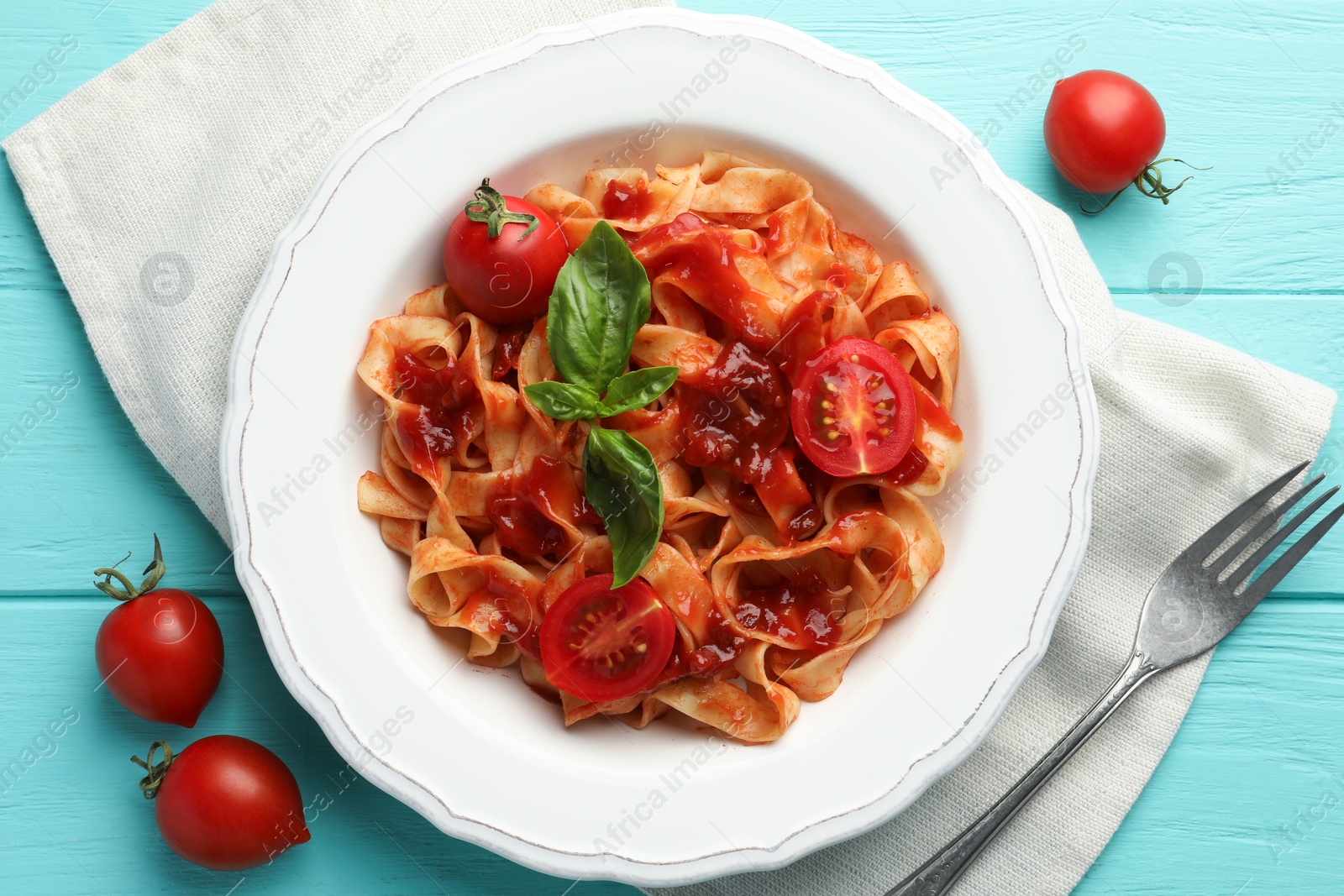 Photo of Delicious pasta with tomato sauce and basil on turquoise wooden table, flat lay