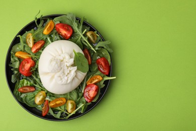 Photo of Delicious burrata salad on green table, top view. Space for text